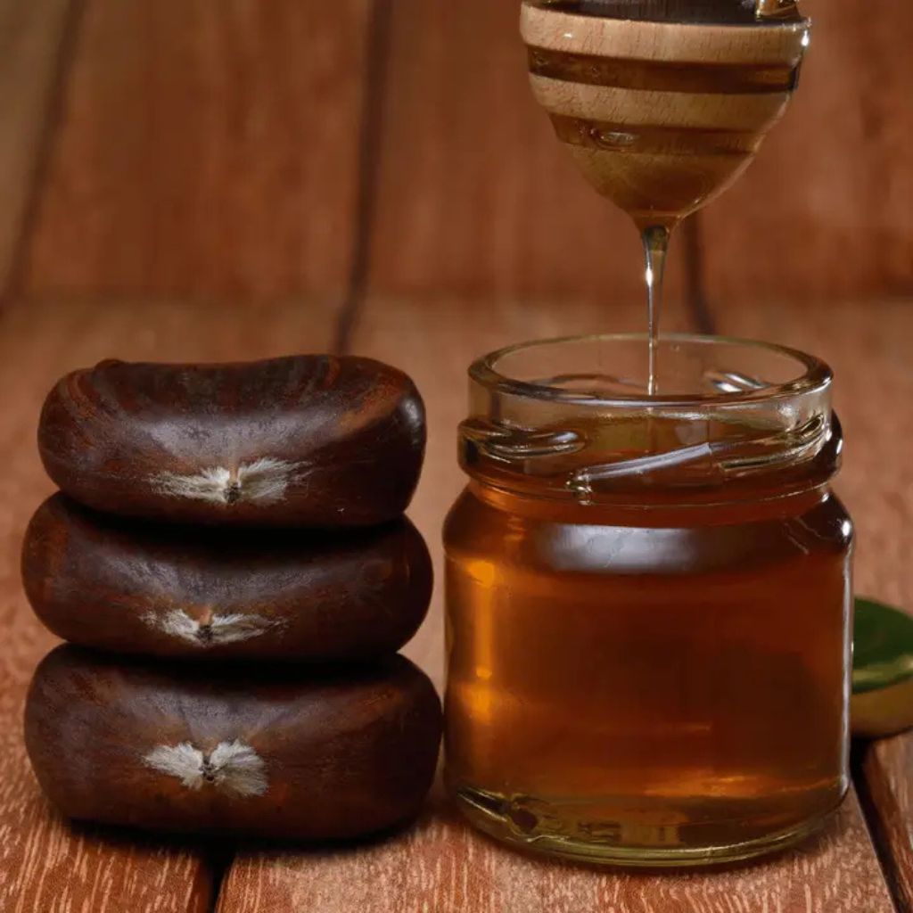 Glas mit dunklem Kastanienhonig, Honiglöffel entnimmt Honig, rötlich-braune Farbe, naturrein und aromatisch.