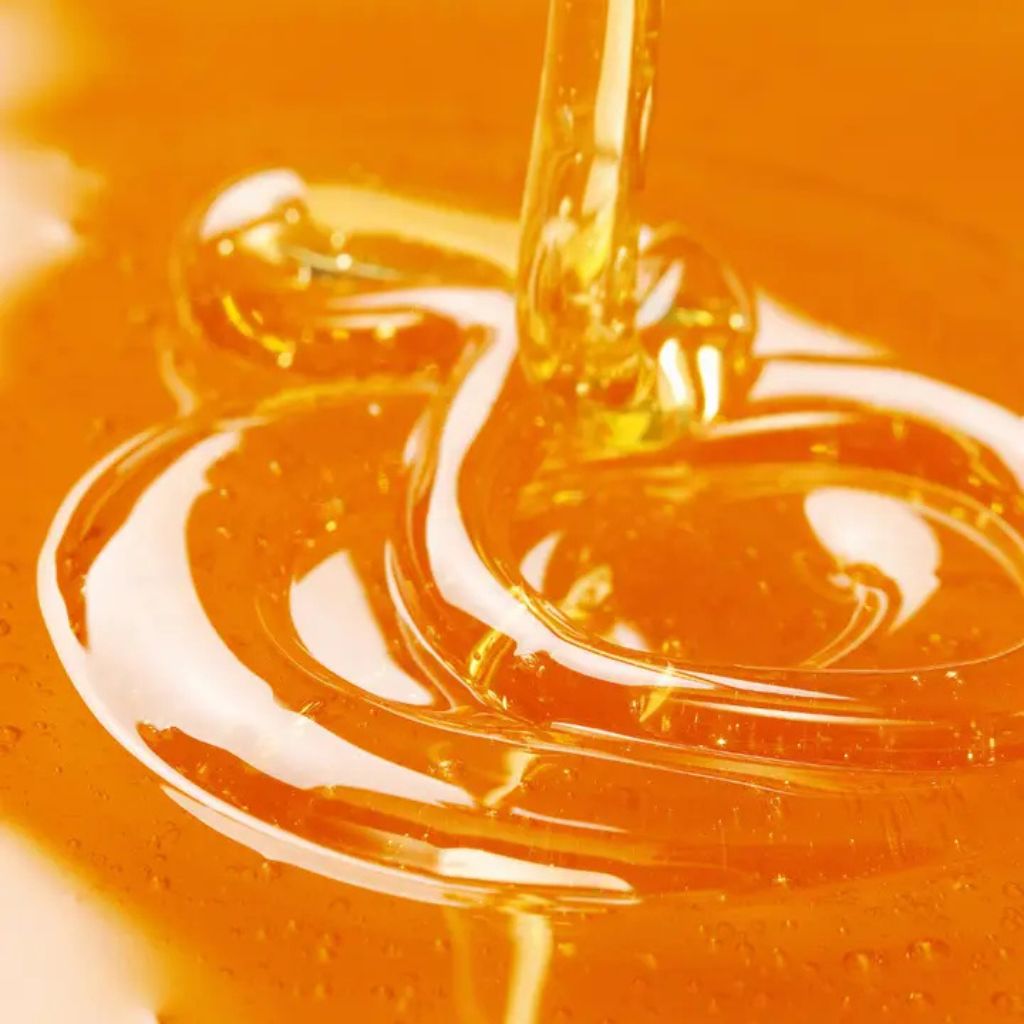 Orangenblütenhonig fließt auf eine Fläche mit Orangenblütenhonig cremige Textur sichtbar