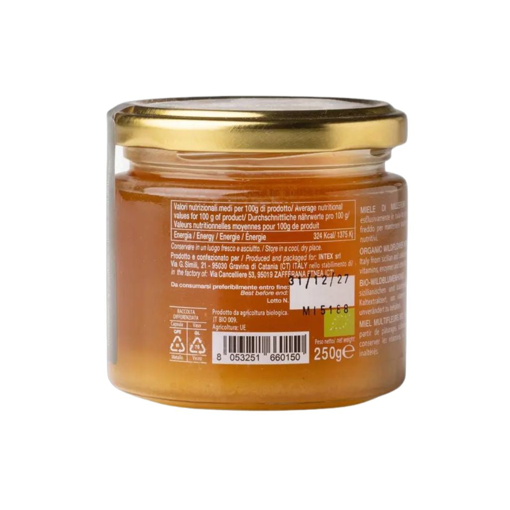 Glas mit bernsteinfarbenem Wildblütenhonig und Deckel, Honig im Glas sichtbar, naturbelassen, cremige Textur, Detailaufnahme der Glasrückseite.